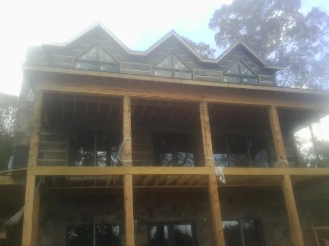 Dormers and porch framing on a large log home under construction — Roof Coating work by our crew in Apple River