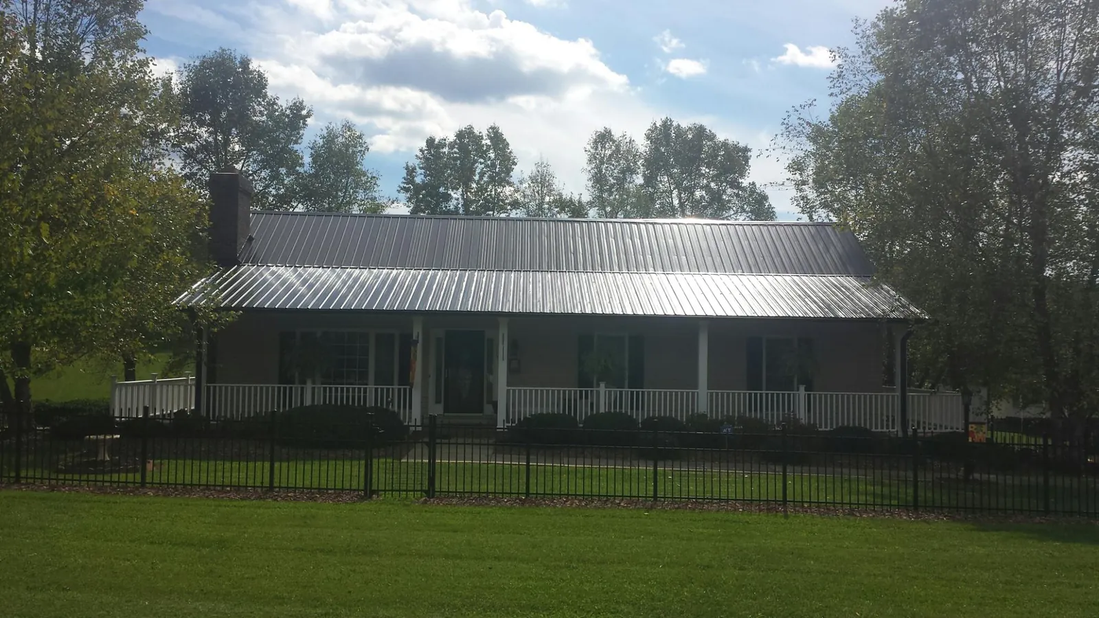 Gray metal roof on a brick ranch with a full width front porch — Gutter Guard Installation work by our crew in Apple River