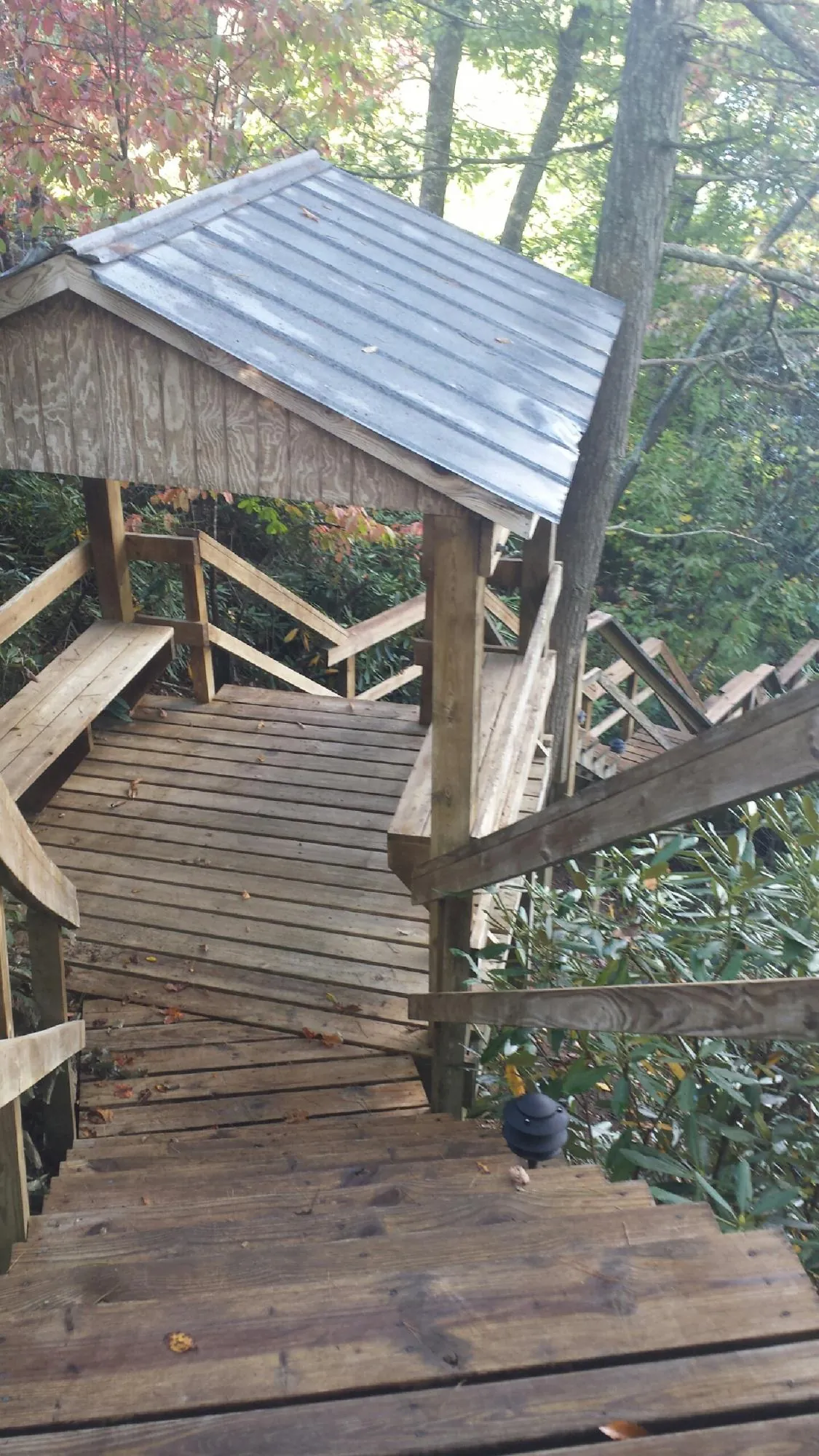Metal roofed shelter over wooden steps on a wooded walkway — Skylight Repair & Installation work by our crew in Apple River
