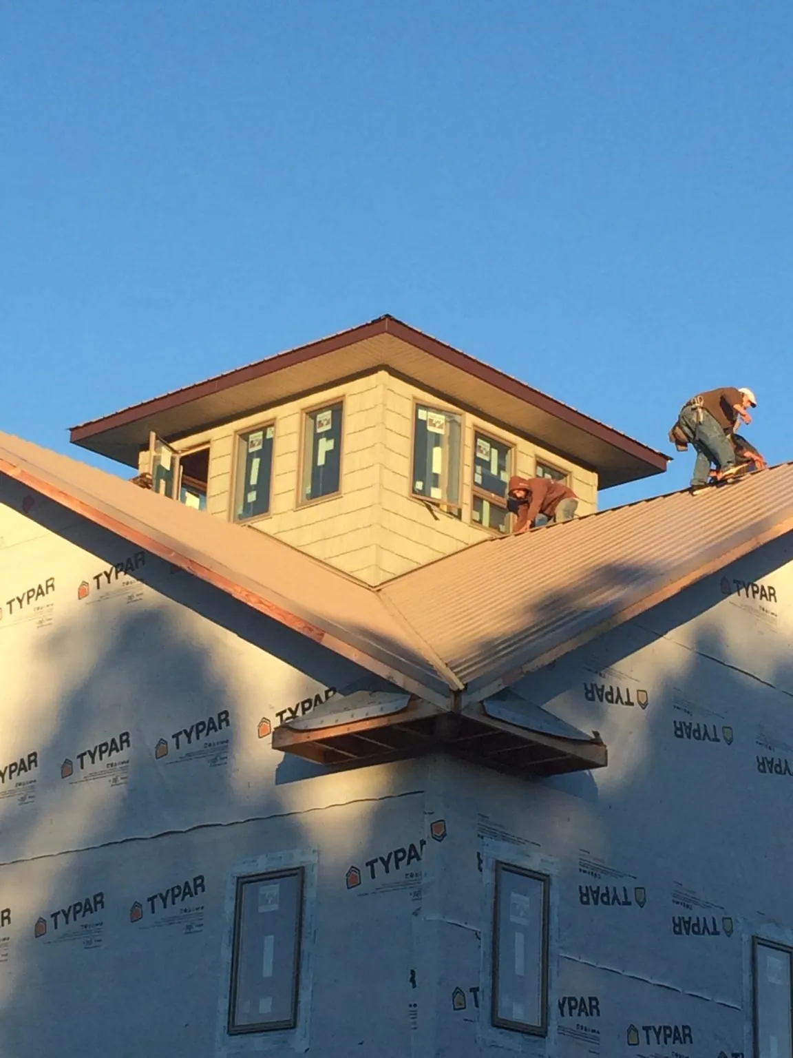 Roofers working around a rooftop cupola on a new metal roof at sunset — Roof Waterproofing in Apple River by Roofing Brothers